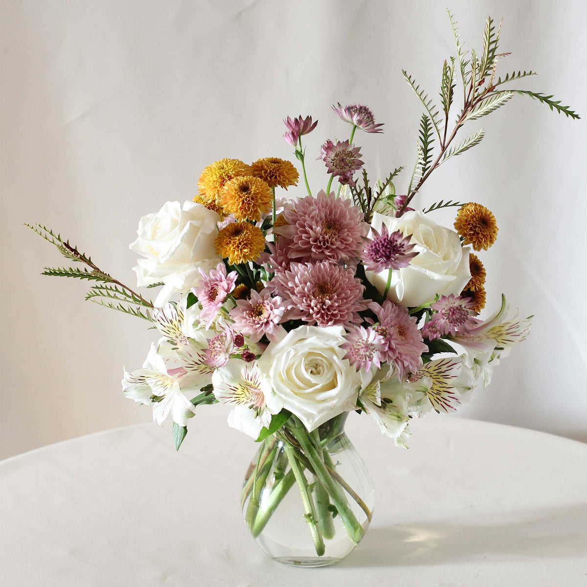 The Quiet Garden floral arrangement featuring golden chrysanthemums, soft lavender flowers, creamy white roses and airy greenery in a garden-inspired design by Flower to Table.